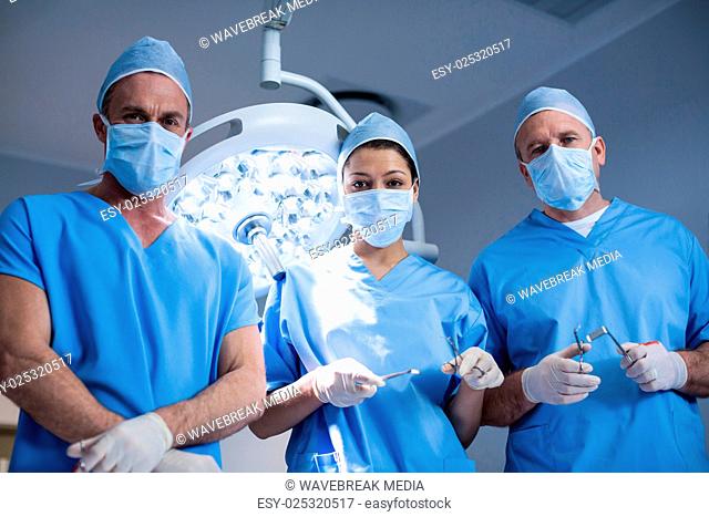 Portrait of surgeons holding surgical tool in operation room