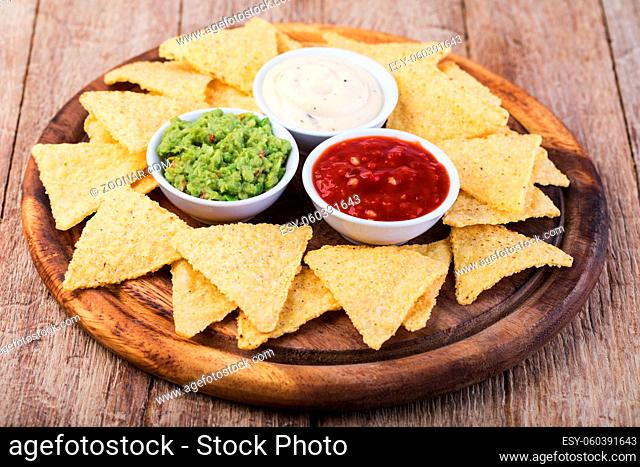 Corn chips nachos with sauce on a wooden table