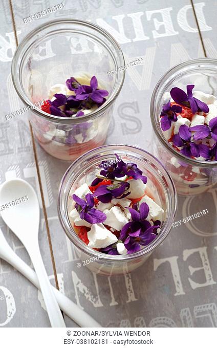 summer dessert with strawberries, vanilla cream, meringue and violet