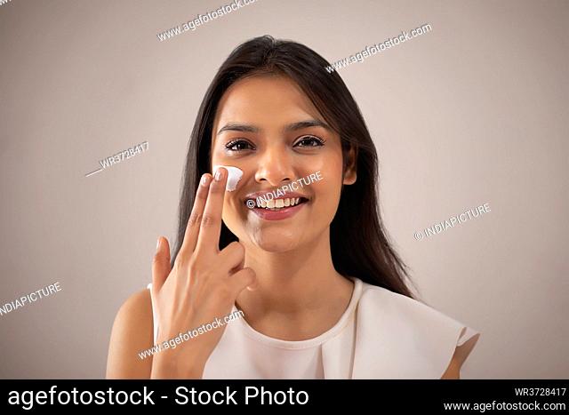 A YOUNG WOMAN HAPPILY PUTTING CREAM ON FACE