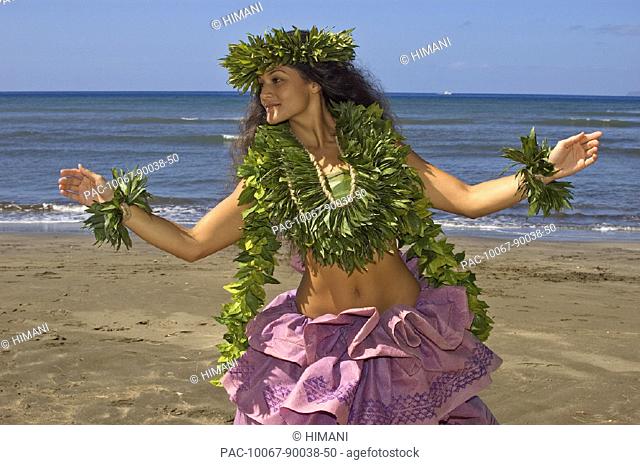 Hula dancer with haku lei in traditional outfit on beach, ocean background