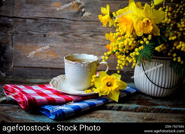 Easter time, spring flowers and cup of tea on the old wooden table