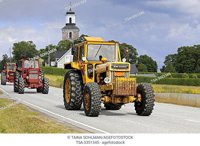 Kimito, Finland. July 6, 2019. Three Volvo BM tractors, yellow 814 first, on Kimito Traktorkavalkad, annual tractor parade through the small town