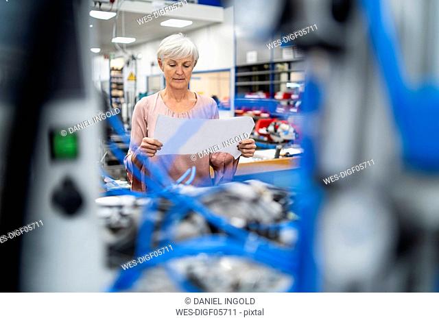 Senior woman looking at plan in a factory