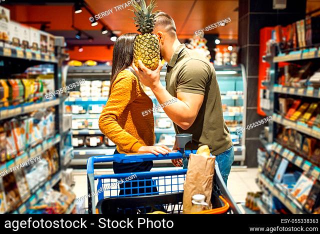 Love family couple kissing in grocery store. Man and woman with cart buying beverages and products in market, customers shopping food and drinks