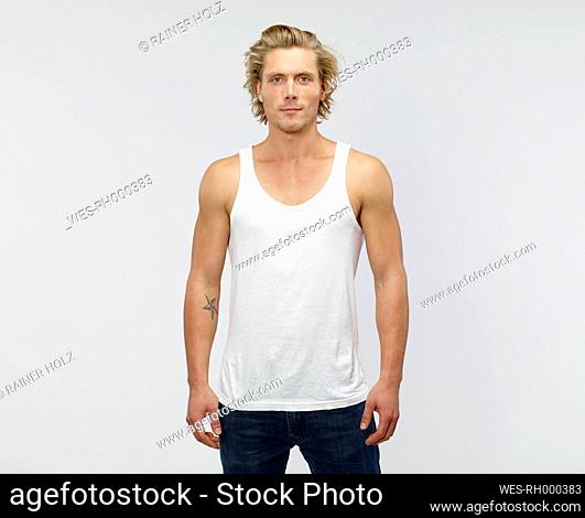 Portrait of young blond man wearing vest in front of white background