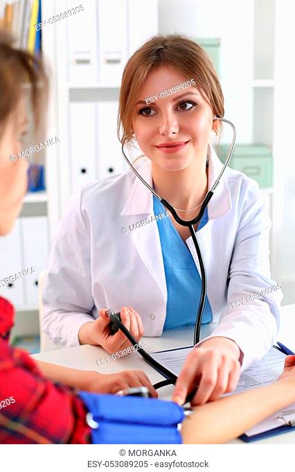 Smiling female medicine doctor measuring blood pressure to her patient. Healthcare, medical and healthy lifestyle concept