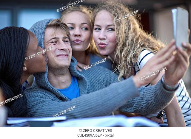 Four young adult friends taking self portrait on smartphone