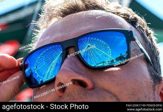 17 June 2022, Saxony, Annaberg-Buchholz: The large Ferris wheel at the Annaberger Kät is reflected in the glasses of a visitor