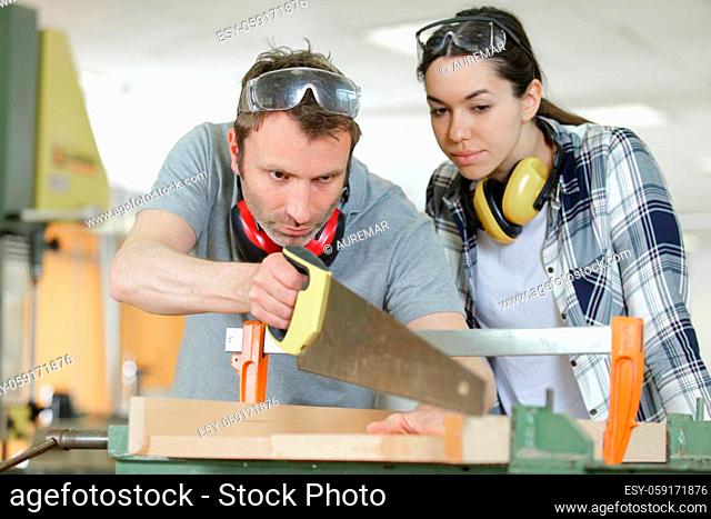 carpenter and apprentice working together in wood workshop
