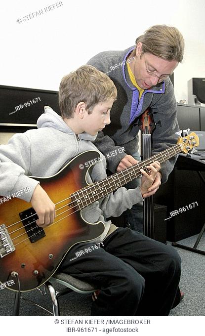 Youth, 15, with his music teacher during a music lesson with a bass guitar in a private music school, Music Academy in Regensburg, Bavaria, Germany, Europe