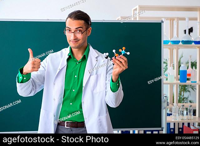 The young male chemist teacher in front of blackboard
