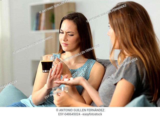 Woman rejecting sugar for the coffee sitting on a couch in the living room at home
