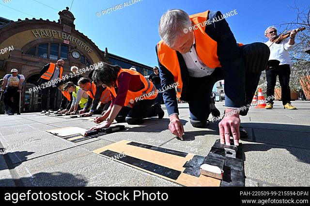 09 May 2022, Thuringia, Erfurt: Andreas Bausewein (r., SPD), Mayor of Erfurt, and others write names on Willy Brandt Square in front of the main train station...