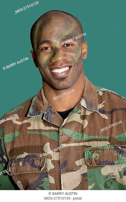 Portrait of an African American male US Marine Corps soldier with camouflaged face over green background