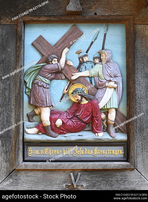 01 April 2021, Bavaria, Eschenlohe: The fifth station on a Way of the Cross up to St. Nicholas on the Vestbichl shows ""Simon of Cyrene helps Jesus carry the...