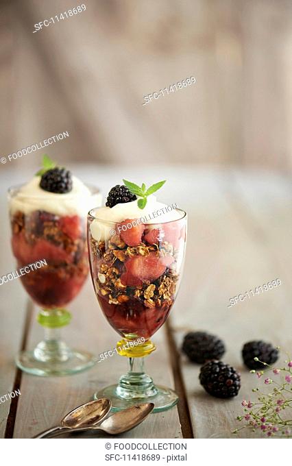 Layered blackberry and apple desserts with cereals and whipped cream