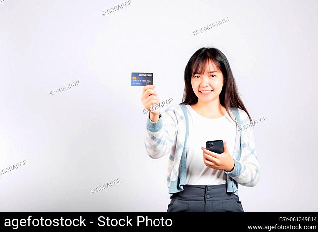 Woman excited smiling hold mobile phone and plastic debit credit bank card for payment studio shot isolated white background