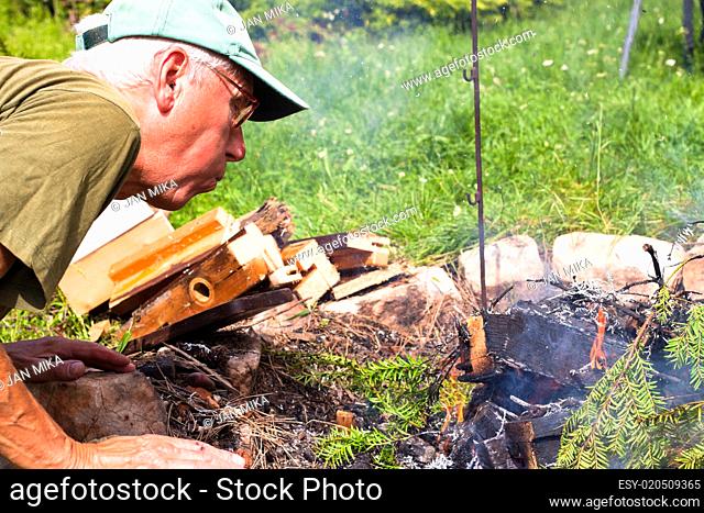 Senior man making bonfire