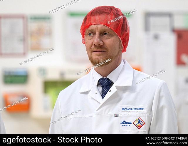 18 December 2023, Saxony, Riesa: Michael Kretschmer (CDU), Minister President of Saxony, wears a hairnet and a smock at the inauguration of a new production...