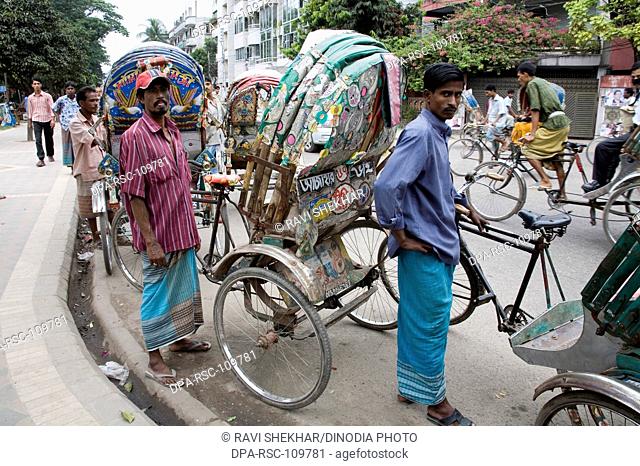 Rickshaw pullers standing on road ; street scene ; Dhaka ; Bangladesh