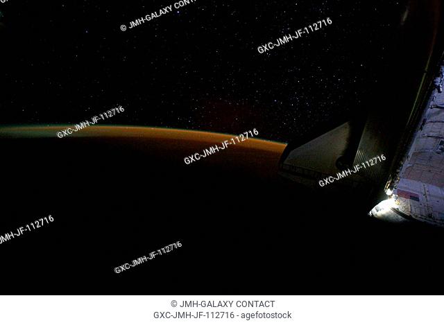 Earth's thin line of atmosphere and a starry sky just off the port wing of the docked space shuttle Endeavour are featured in this image photographed by NASA...