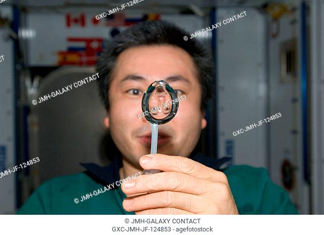 Japan Aerospace Exploration Agency (JAXA) astronaut Koichi Wakata, Expedition 20 flight engineer, squeezes a water bubble out of his beverage container