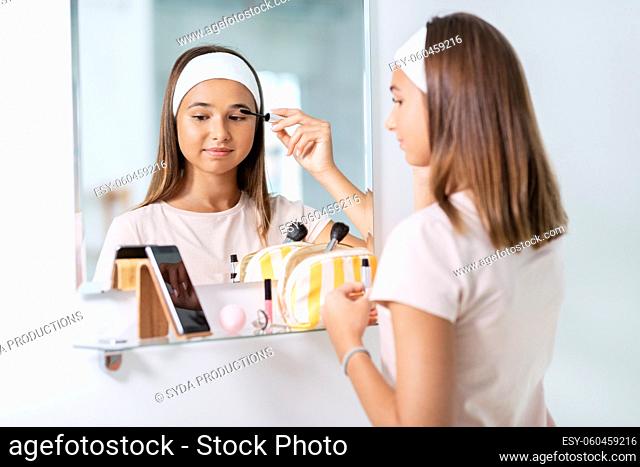 teenage girl applying mascara at bathroom