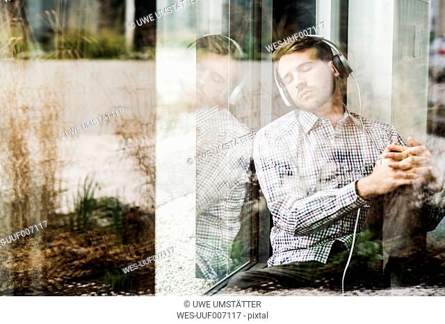 Young man sitting at the window wearing headphones
