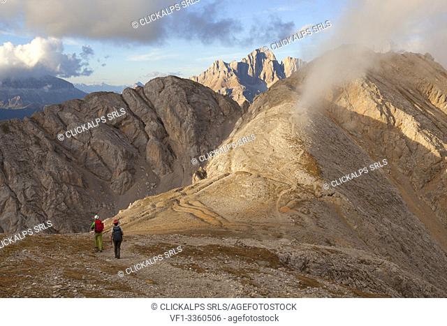 Two hikers descend from the summit of Cima della Campagnaccia along the Bepi Zac High Trail, Costabella Ridge, Marmolada group, Dolomites, Moena, Fassa Valley
