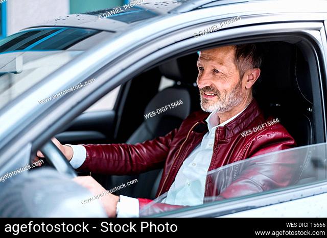 Smiling mature man driving car