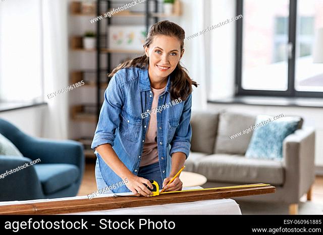 woman with ruler measuring wooden board at home
