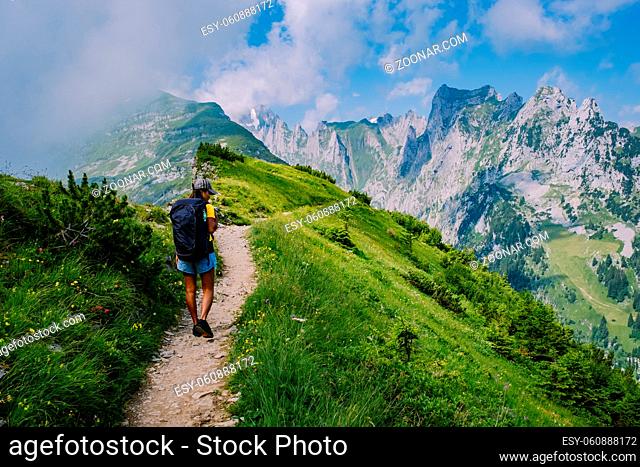 A woman with a backpack stands on top of a mountain, The girl travels to beautiful places, Reaching the goal, mountain ridge at Saxer Lucke