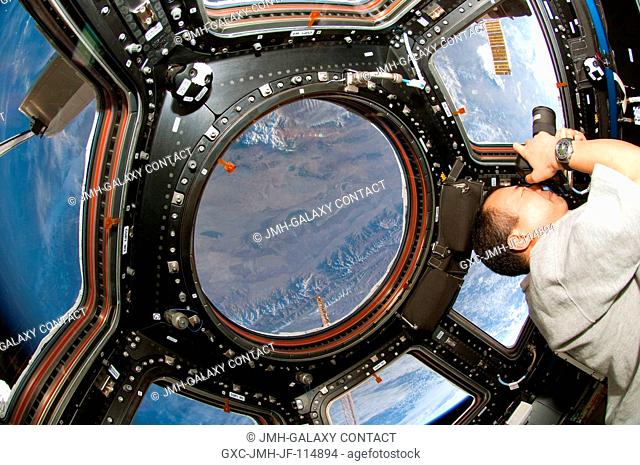 Japan Aerospace Exploration Agency (JAXA) astronaut Soichi Noguchi, Expedition 22 flight engineer, uses a still camera at a window in the Cupola of the...