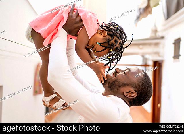 Cheerful man lifting daughter