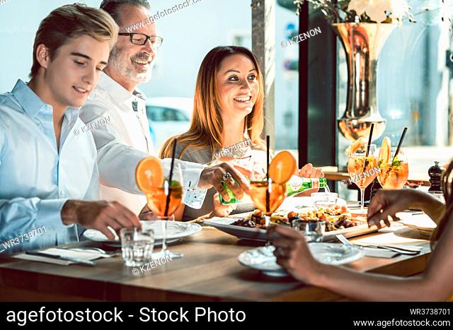 Blond beautiful woman served by an experienced waiter while having lunch with her best friends at a trendy restaurant