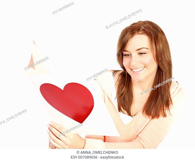 Image of happy beautiful female reading romantic greeting card with big red heart, attractive brunette woman got love letter