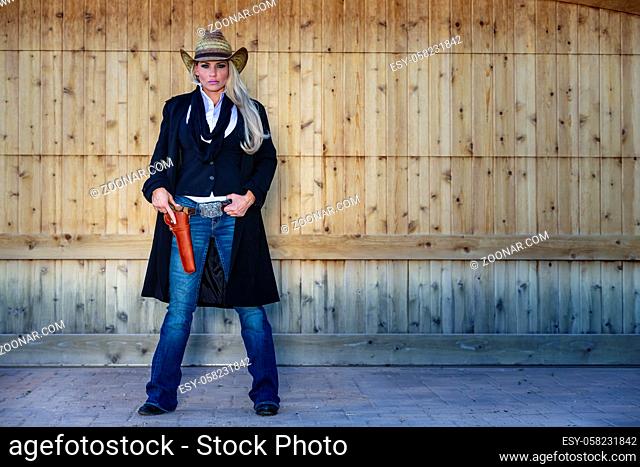A blonde model posing as a cowgirl in a western environment