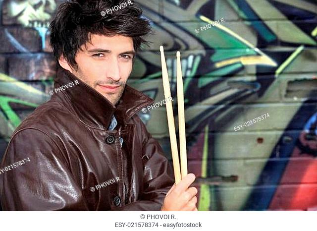 musician with drumsticks against graffiti wall