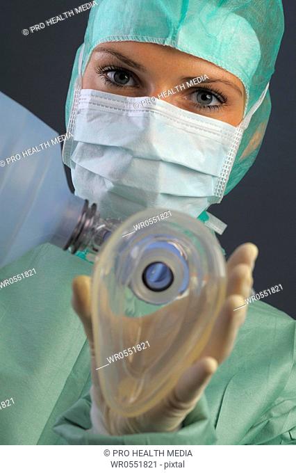 young woman with respiratory mask and ambu bag in an operation room. She is wearing a mouth mask and a bonnet