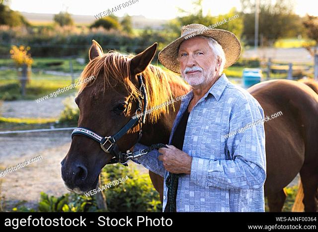 Senior man standing by horse at farm