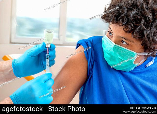 Male doctor in protective face mask latex gloves giving intramuscular vaccination into patient's arm