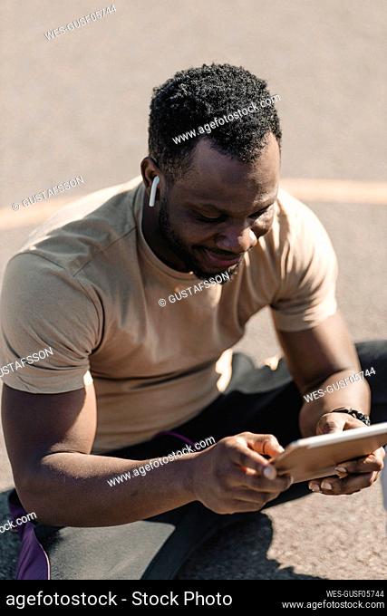 African man using digital tablet while listening music through wireless headphones