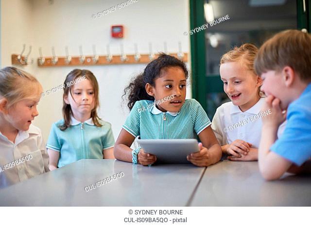 Schoolgirls and boy using digital tablet in classroom lesson at primary school