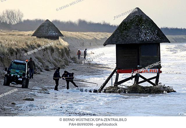 Workers look at a severely damaged lifeguard's tower on the Baltic coast on the peninsula of Fishland near Graal-Mueritz, Germany, 05 January 2017