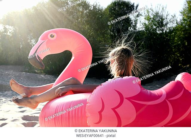Girl sitting on flamingo pool float