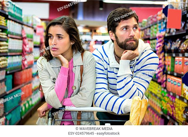 Bored couple with shopping trolley in organic section