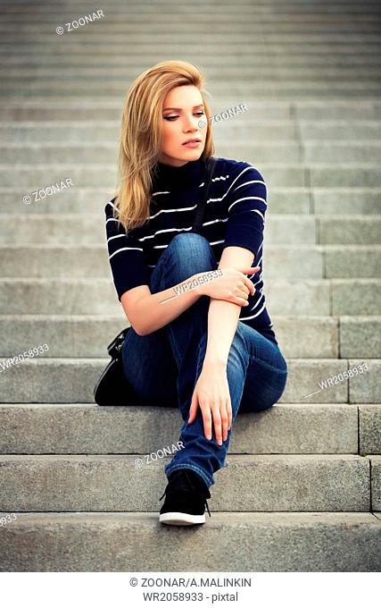 Beautiful girl with bare legs is sitting on stairs, Stock Photo