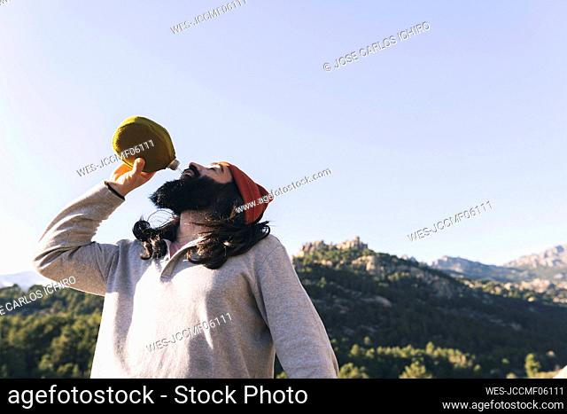 Bearded man drinking water on sunny day