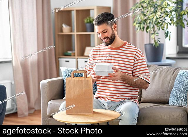 smiling man unpacking takeaway food at home